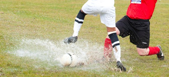 Football players tackling on a wet pitch -image to represent transforming lives through sport